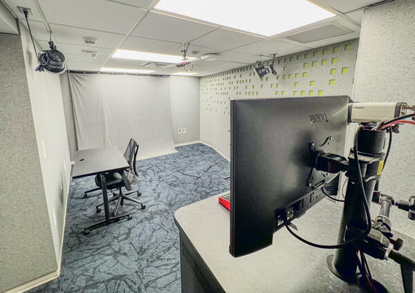 Recording studio with video camera, lighting, backdrop, and big green and red buttons.