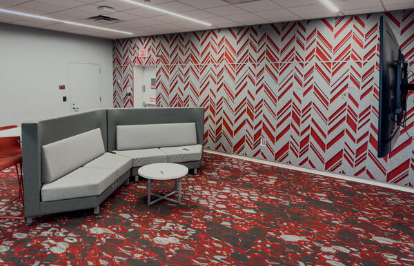 Seating in large room with red patterned carpeting and wall-mounted display