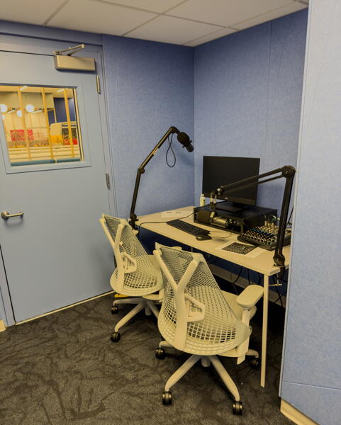 Two chairs at an audio podcast station with a computer and microphones