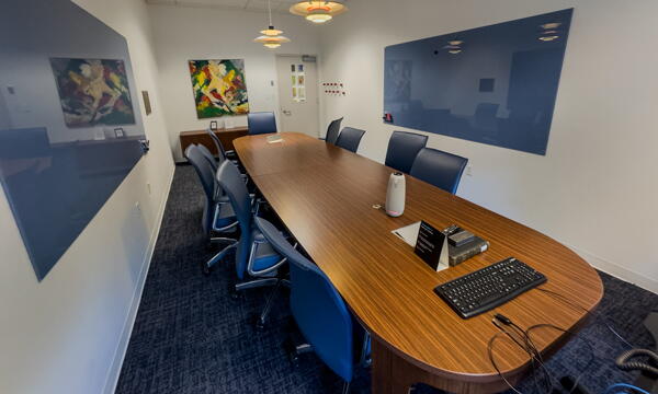 Conference room with long wood table, chairs, two dry erase boards, and technology