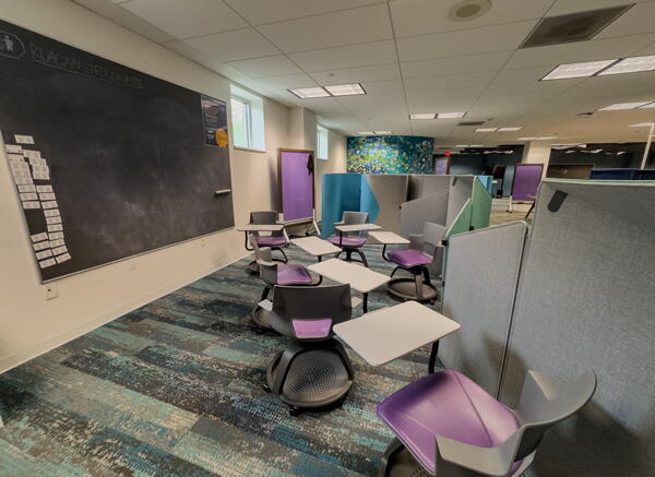 Movable chairs with attached individual desks in front of a large chalkboard