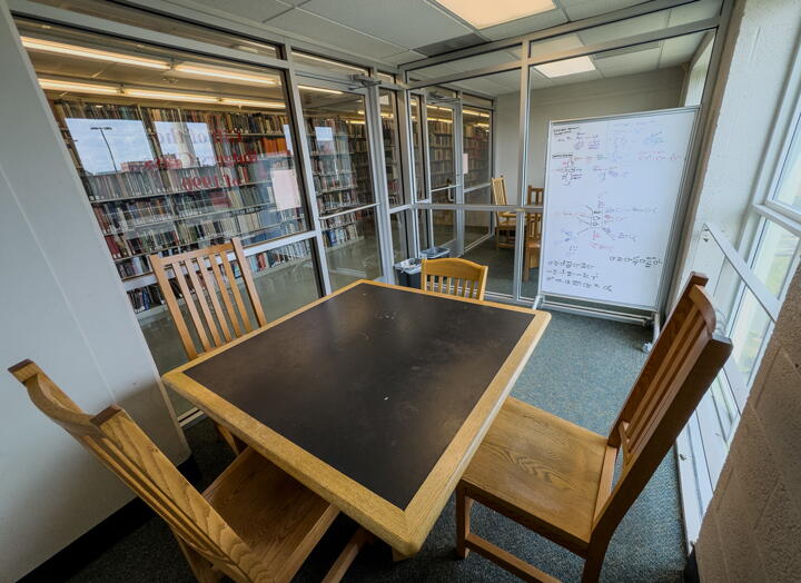 Interior of group study room with square table, four chairs, and a whiteboard