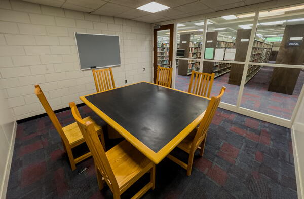 Interior of group study room with group table, six chairs and a wall-mounted chalkboard