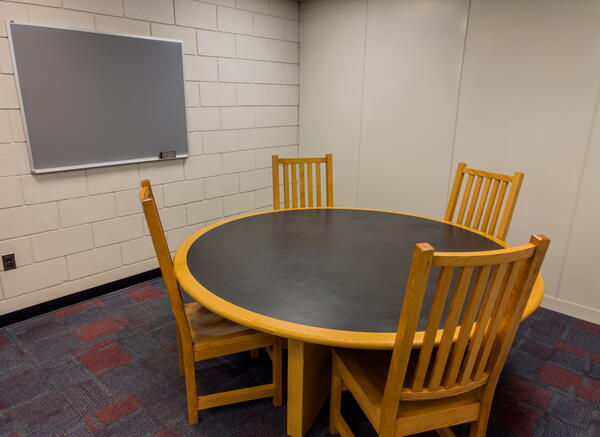 Study room with small group table with four chairs and a wall-mounted chalkboard