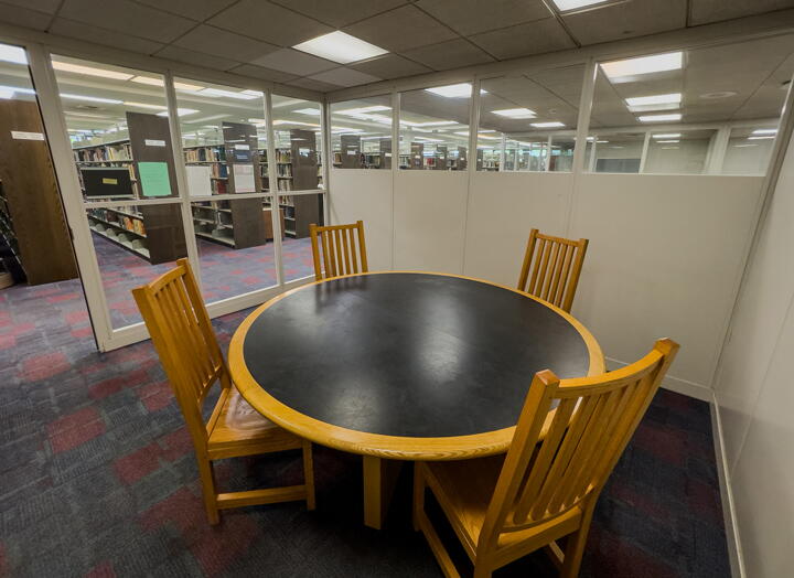 Interior of group study room with small round table with four chairs and a glass wall