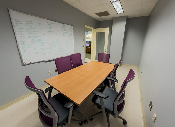 Interior of group study room with a large table, chairs, and a whiteboard wall