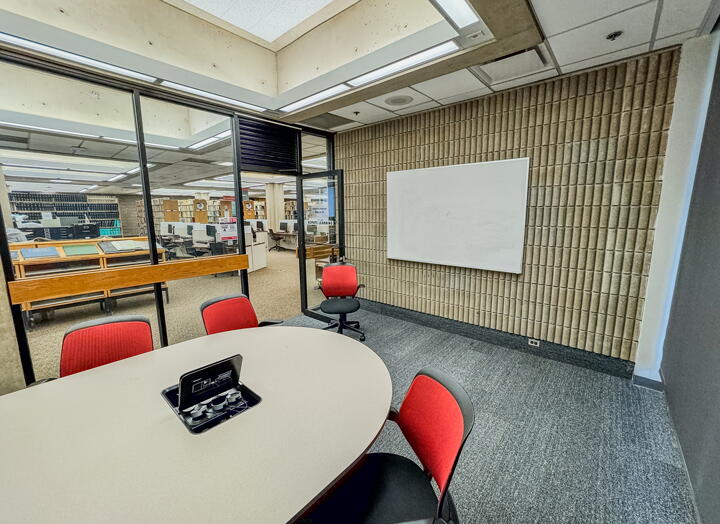Interior of study room with table, chairs, and wall-mounted whiteboard