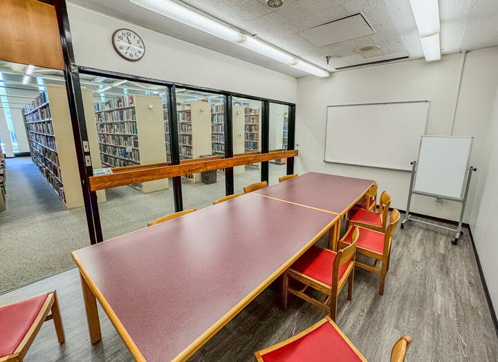 Group study room with table, chairs, clock, and wall-mounted and standing whiteboards