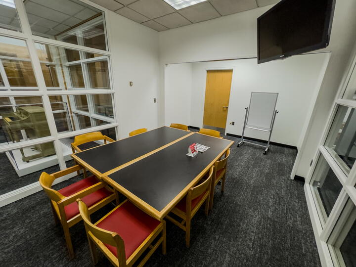 Group study room with a table, chairs, whiteboard, and a large display