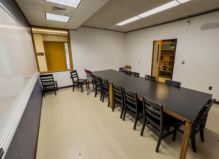Interior of group study room with a large table, 12 chairs, and a whiteboard wall