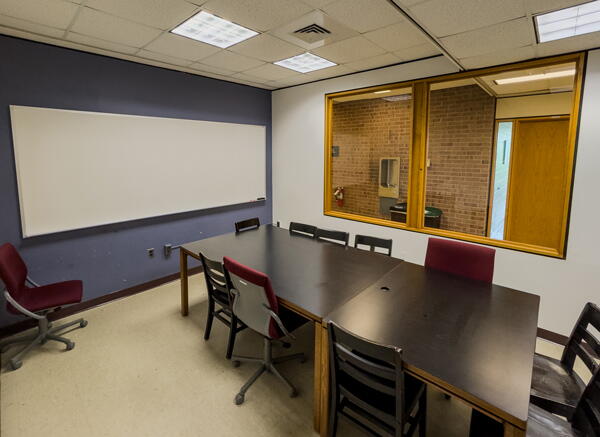 Interior of group study room with a large table, chairs, and a whiteboard wall
