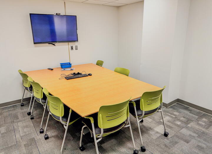 Interior of group study room with a large table, chairs, and a wall-mounted display