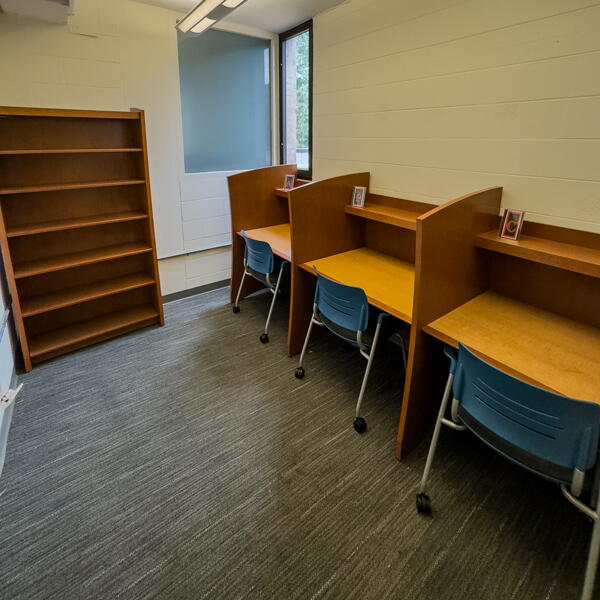Three individual study carrels and empty bookshelves