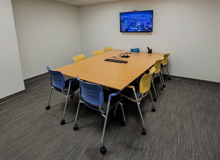 Interior of group study room with a large table, chairs, and a video display