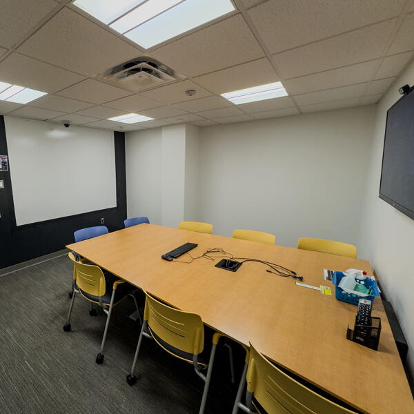 Interior of group study room with a large table, chairs, a video display, and a large wall-mounted whiteboard