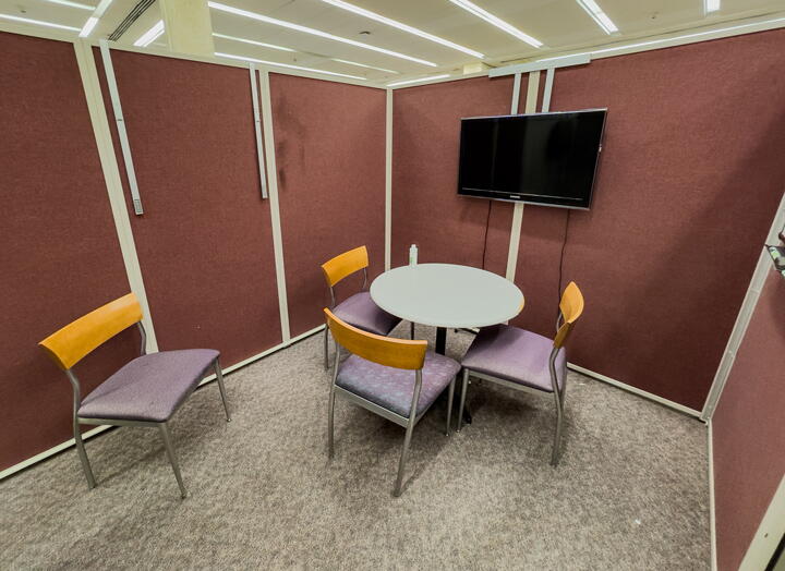Small group study room with round table with four chairs and a wall-mounted display