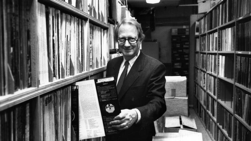 Black and white photo of Dan Morgenstern, former director of the Institute of Jazz Studies, pulling out a record from the IJS collection