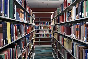 Image of book shelves filled with books there are two shelves that lead down a corridor, with more bookshelves at the end