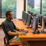 Man working on computer at long table with many computers